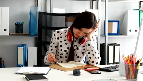 Frau-mit-roten-Kopfhörer-auf-Schultern-blätterte-Buch-im-modernen-Büro