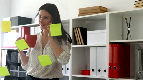 businesswoman-in-white-blouse-considering-stickers-on-glass-and-talking-on-phone