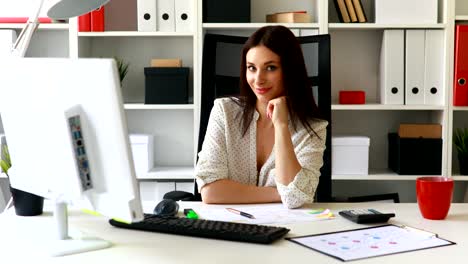 businesswoman-leaning-her-chin-and-looking-at-camera-in-office