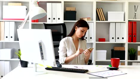 geschäftsfrau-im-Bürostuhl-sitzen-und-mit-smartphone