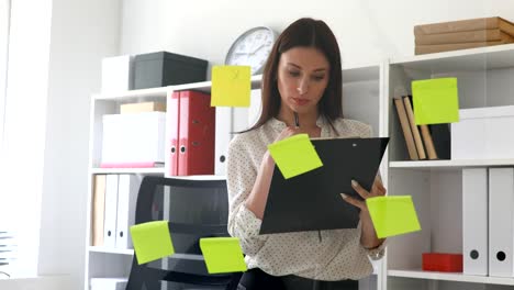 businesswoman-making-notes-in-documents-standing-near-glass-wall