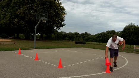 Athlet-sammelt-orange-Kegeln-aus-dem-Basketballplatz