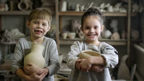 Glückliche-kleine-Kinder-posiert-in-der-Keramikwerkstatt