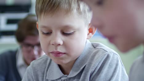 Face-of-Boy-Studying-with-Classmates-at-School