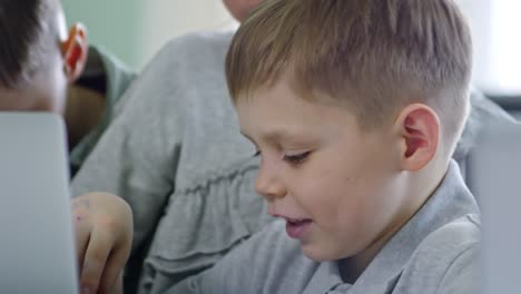 Junge-Lächeln-wenn-mittels-Laptop-mit-Klassenkameraden