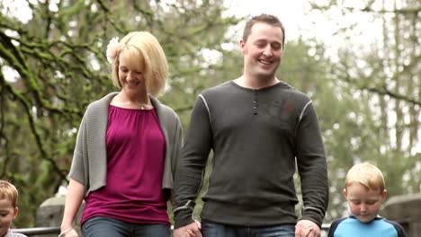 A-mother-and-father-hold-their-sons-hands-as-they-walk-down-some-park-stairs