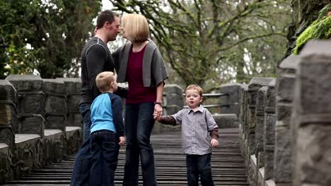 Una-mamá-y-un-papá-con-sus-dos-hijos-caminar-por-un-conjunto-de-escaleras-en-un-parque-y-un-beso