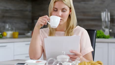 Hübsche-Frau-mit-Dokumenten-arbeiten-und-Kaffeetrinken-zu-Hause