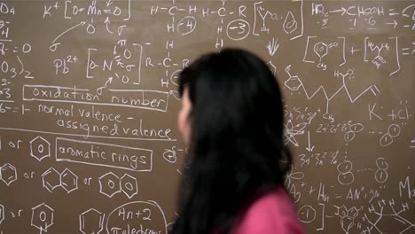 A-female-Asian-university-student-stands-in-front-of-a-blackboard