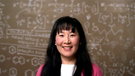 A-female-Asian-college-student-stands-in-front-of-a-blackboard-with-equations