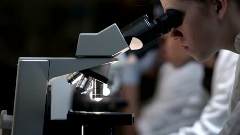 University-Students-in-a-lab-look-through-a-microscope-during-their-class