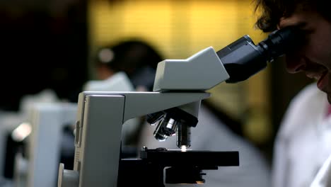 Students-in-a-laboratory-look-through-a-microscope-during-their-experiments