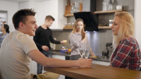 Gente-joven-con-gafas-de-champán-hablando-en-la-cocina