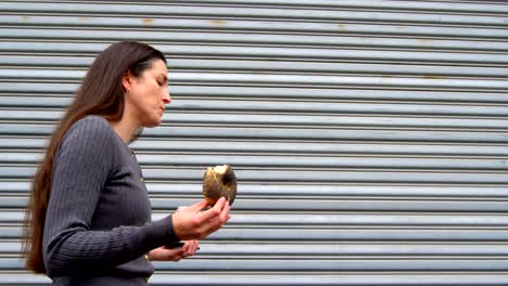 Beautiful-woman-having-donuts-while-walking-in-city