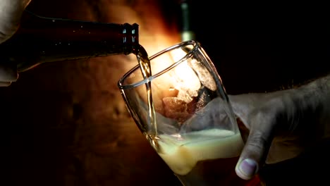 man-pouring-fresh-beer-with-foam-into-drink-pint-glass-with-ice-frozen-drops,-on-gold-brown-background,-fun-and-nutrition-food