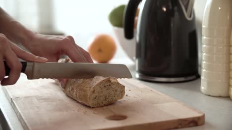 Cutting-Bread-On-Wooden-Board-By-Woman-Hands-Closeup