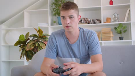 Closeup-portrait-of-adult-attractive-caucasian-man-playing-video-games-sitting-on-couch-indoors