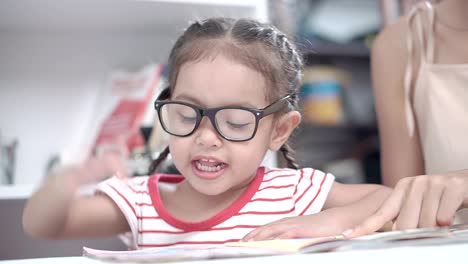 A-little-girl-sitting-and-reading-with-her-mother.