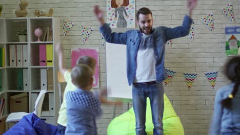 Playful-Kids-Exercising-with-Male-Teacher-in-Kindergarten