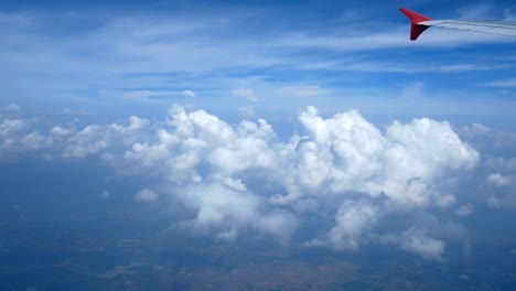 4K-Filmmaterial.-Reisen-mit-dem-Flugzeug.-Blick-durch-ein-Flugzeugfenster.-Flügel-Flugzeug-und-schöne-weiße-Wolken-am-blauen-Himmel-Hintergrund