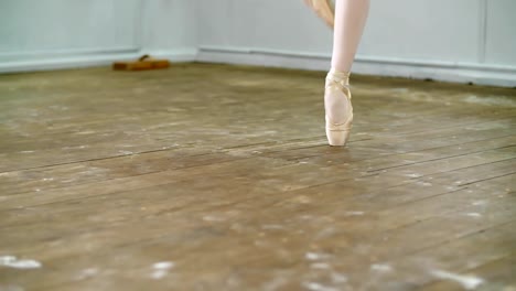 cerca,-en-el-salón-de-baile,-bailarina-realizar-simples-ssissonne,-ella-está-de-pie-en-los-pies-en-los-zapatos-del-pointe-con-elegancia,-en-un-viejo-piso-de-madera,-en-clase-de-ballet