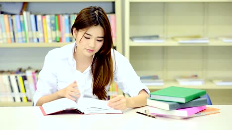 Studie-schwer-in-der-Bibliothek.-Junge-Chinesin-Studium-hart-an-der-Bibliothek.