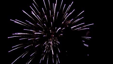 Beautiful-colors-of-fireworks-in-the-night-dark-sky.-A-bright-ball-of-crimson-color-opens,-and-in-its-center---a-dense-light-ball.-Against-the-background-of-fireworks-you-can-see-the-figure-of-a-happy-man