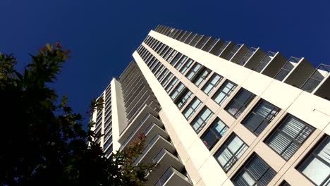 Bewegung-der-hohen-Aufstieg-Gebäude-und-bläst-Baum-Blatt-gegen-blauen-Himmel