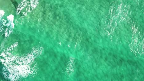 Aerial-shot-of-transparent-sea-water-wit-waves-crashing