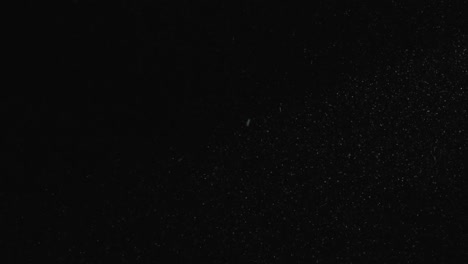 Weiße-Partikel-fliegen-auf-schwarzem-Hintergrund