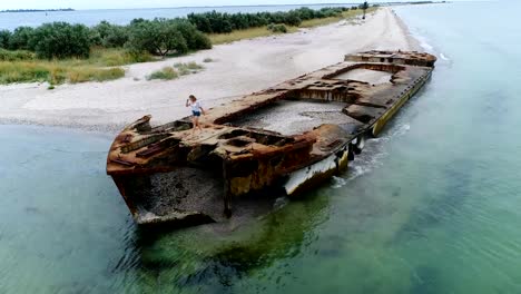 Young-woman-walking-on-a-shipwreck