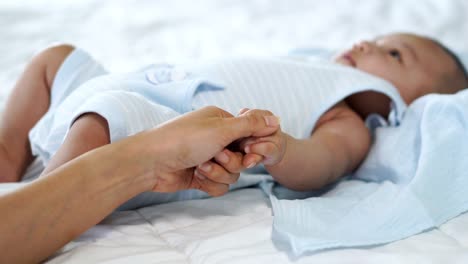 Baby-Hand-halten-Finger-der-Mutter-auf-einem-Bett