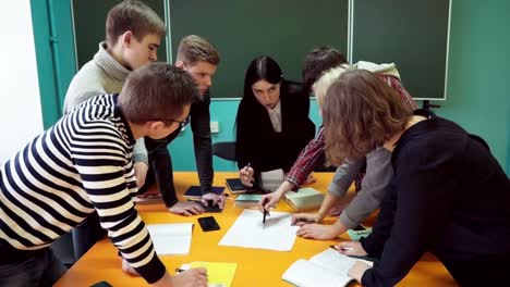 Grupo-de-jóvenes-estudiantes-haciendo-la-tarea-bajo-la-supervisión-del-profesor