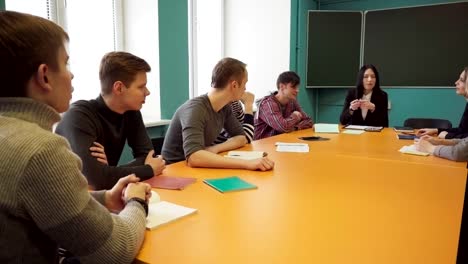 Group-of-students-and-a-teacher-sit-at-a-table-and-talk