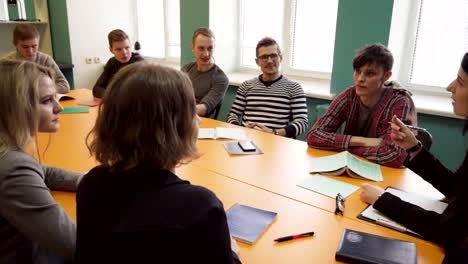 Maestro-se-sienta-en-una-mesa-y-habla-con-estudiantes-en-la-Universidad-de