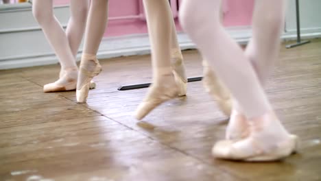 in-ballet-hall,-Young-ballerinas-perform-pas-echappe-in-pointe-shoes,-goes-up-on-toes,-close-up