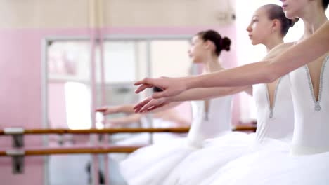 in-ballet-hall,-Young-ballerinas-perform-allonge,-moving-hands-elegantly-up-and-down,-close-up