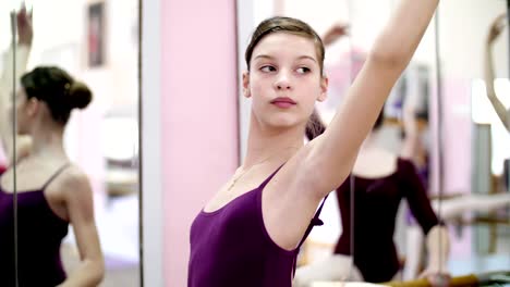 in-ballet-hall,-Young-ballerina-in-purple-leotard-perform-a-slope,-bend-back,-tilt-back,-moving-hand-elegantly-up-and-down,-standing-at-railing-in-hall.-close-up