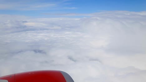 Clouds-from-the-window-of-an-airplane,-red-engine.