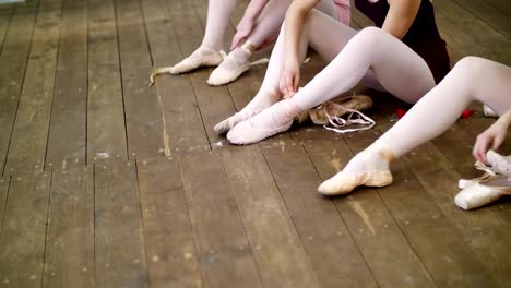 cerca,-bailarinas-cambian-sus-zapatos-en-especial-ballet-zapatos,-zapatos-de-punta,-encaje-con-cintas-de-ballet,-en-un-viejo-piso-de-madera,-en-clase-de-ballet