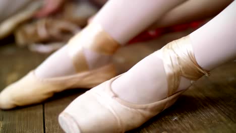 in-der-Nähe-ändern,-Ballerinas-ihre-Schuhe-in-speziellen-Ballettschuhe,-Spitzenschuhe,-Spitze-mit-Ballett-Bändern,-auf-einem-alten-Holzboden-in-Ballett-Klasse