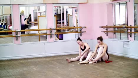 Ballerinen-ändern-ihre-Schuhe-in-speziellen-Ballettschuhe,-Spitzenschuhe,-Spitze-mit-Ballett-Bändern,-auf-einem-alten-Holzboden-in-Ballett-Klasse