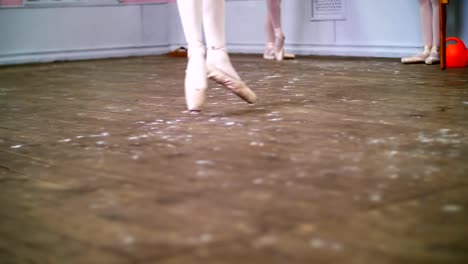 close-up,-in-ballet-class,-on-an-old-wooden-floor,-ballerina-performs-glissade-en-tournant,-She-moving-through-the-ballet-class-elegantly