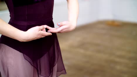 close-up,-in-dancing-hall,-Young-ballerina-in-purple-leotard-performs-first-position-of-hands,-elegantly