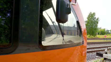 The-side-mirror-of-the-big-orange-train-in-the-station