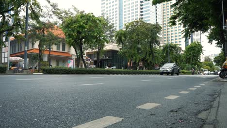 The-carriageway-in-the-city-center-with-motorbikes-and-cars,-office-buildings-in-the-background