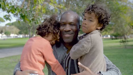 African-American-dad-abrazando-a-niños-rizados-en-el-parque-de-verano