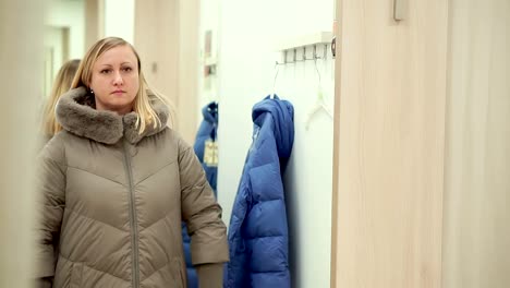 A-woman-in-a-clothing-store,-chooses-a-new-down-jacket