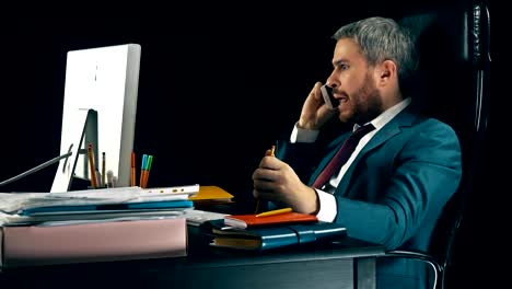 Angry-bearded-businessman-having-emotional-stressful-conversation-on-his-cell-phone.-Black-background.-FullHD-video