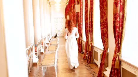 Hermosa-mujer-en-traje-vintage-de-la-bola-con-el-ventilador-en-su-mano-está-caminando-en-la-sala-de-la-bola